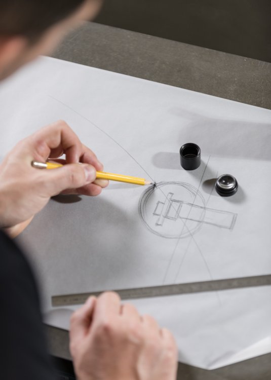 Ein Produktdesigner entwift eine Leuchte auf weissem Papier mit gelbem Bleistift