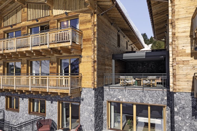 Chalet aus hellem Holz, unterstes Geschoss in Naturstein.