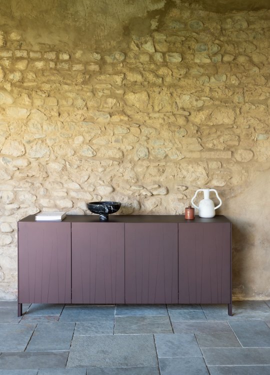 Weinrotes Aluminium-Sideboard vor einer bräunlichen Steinwand.
