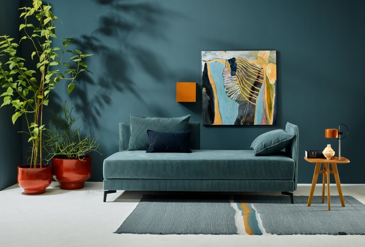 Petrolfarbenes Dana Daybed vor gleichfarbiger Wand mit Zimmerpflanzen und Teppich