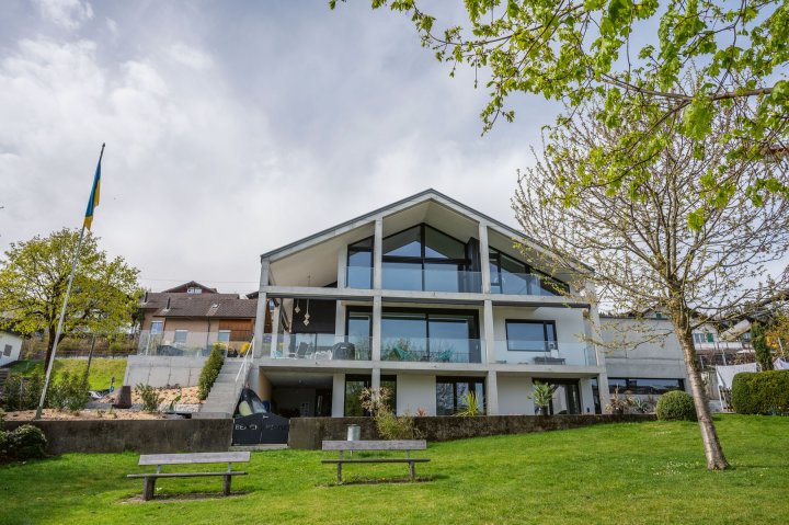 Haus mit Satteldach und verglasten Fronten auf grüner Wiese