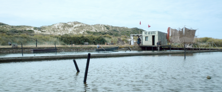 Strand mit bewachsenen Sanddünen und einem kleinen Unterschlupf