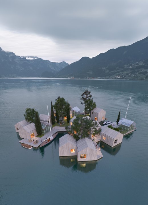 Eine schwimmende kleine Siedlung aus Holzhäusern vor einer Bergkulisse