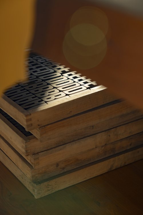 Holzschubladen mit Druckbuchstaben in warmem Licht; im Vordergrund ist der Schriftzug «SHEPARD FAIREY» erkennbar.