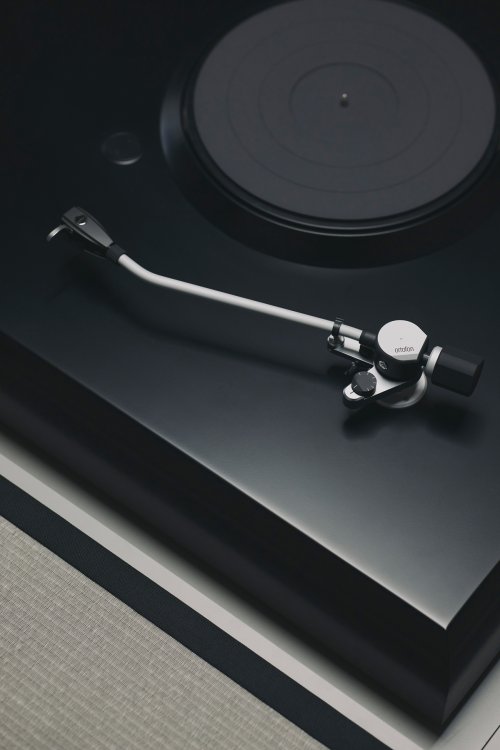 Detailansicht eines minimalistischen Plattenspieler-Moduls in mattem Schwarz mit einem weissen Tonarm von Ortofon. Das Gerät ist bündig in eine Bodenfläche neben Tatami-Matten eingelassen, was die Verschmelzung von Hi-Fi-Technik und Inneneinrichtung zeigt.