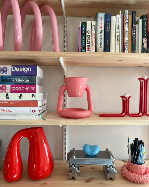 Regal mit Gustaf-Westman-Objekten in Bonbonfarben, darunter der Spiral Stand, der Chunky Coffee Maker und der Chunky Jug zwischen Büchern und weiteren Designobjekten.