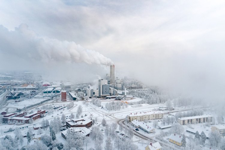 Vogelperspektive auf ein Biomassekraftwerk im verschneiten Lappeenranta, aus dessen Schornsteinen dichte Weissdampfwolken aufsteigen.