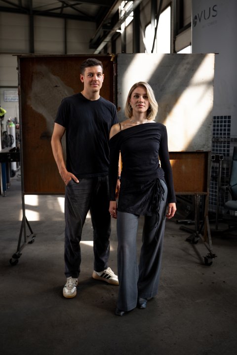 Vera und Sämi Zumstein stehen in einer Werkstatt vor Metallplatten.