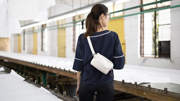 Rückansicht von Frau in dunklem Shirt mit heller Tasche über den Schultern