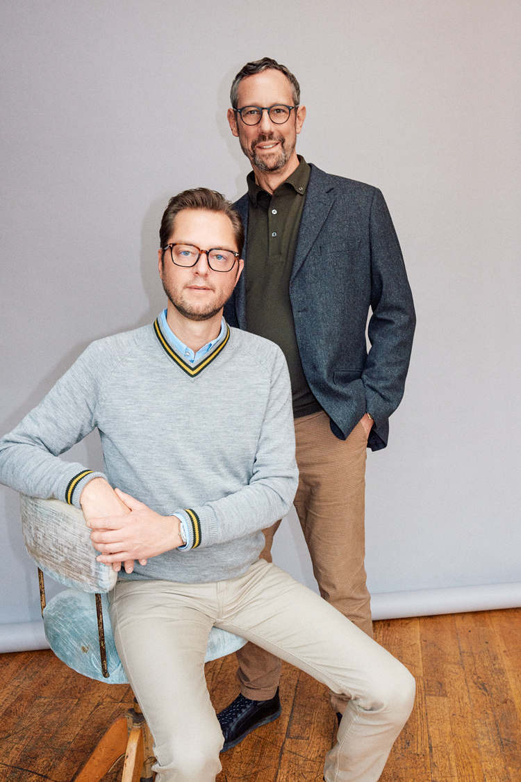 Porträtfoto von zwei Männern, links sitzt einer von ihnen, der andere steht rechts dahinter