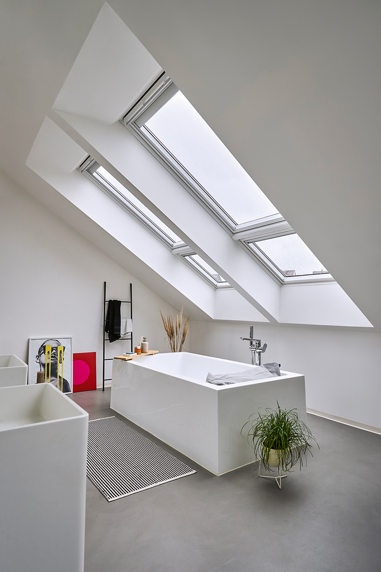 eine Badewanne steht in einem Dachraum unter einem doppelten Dachfenster