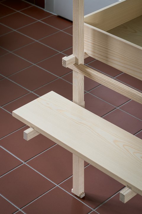 Ausschnitt eines Holzregals auf einem roten Tonboden