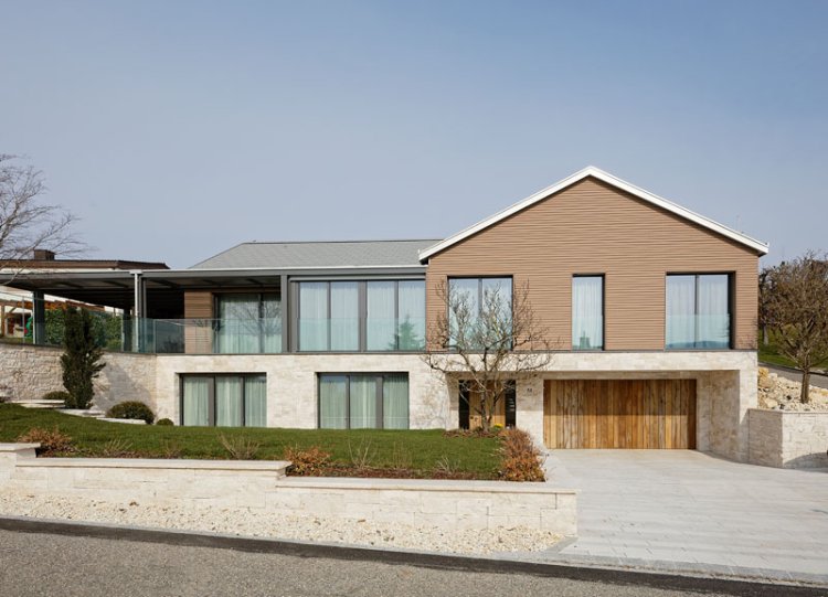 Aussenansicht modernes Holzhaus mit Giebeldach und seitlichem Anbau.