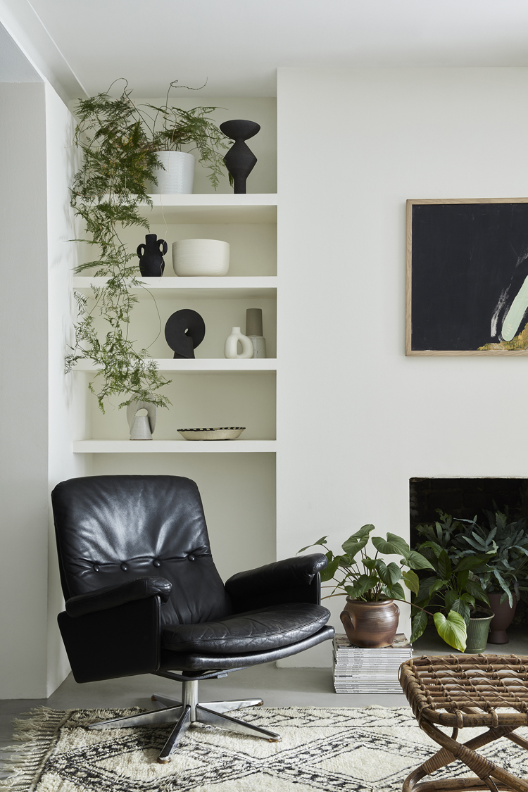 Moderne Leseecke mit schwarzem Ledersessel vor Regalwand.