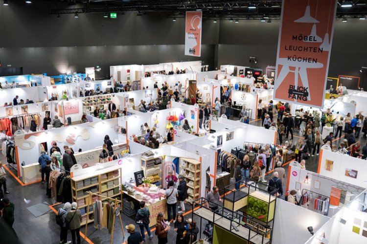 Blick von oben auf die Messehalle der Blickfang Basel mit verschiedenen Ständen und Besucher*innen.