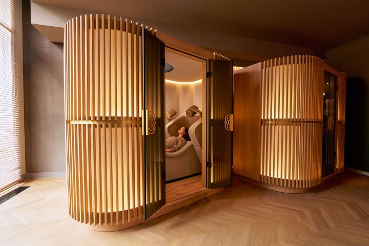 Person liegt entspannt in einem beleuchteten, holzverkleideten Pod für die Brain Massage der Mind Oasis.