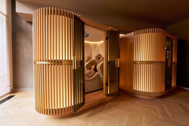 Person liegt entspannt in einem beleuchteten, holzverkleideten Pod für die Brain Massage der Mind Oasis.