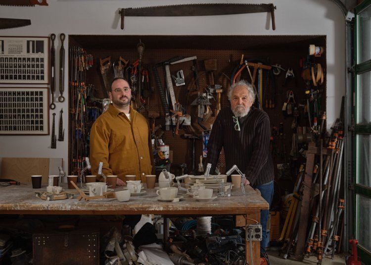 Michael Yarinsky und Allan Wexler stehen in einer Werkstatt vor einem Arbeitstisch mit Werkzeugen und Modellen.