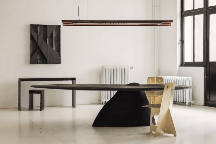 Zeitgenössischer Tisch und Stühle aus dunklem und hellem Material in einem minimalistischen, lichtdurchfluteten Innenraum mit Fenster und Heizkörpern.