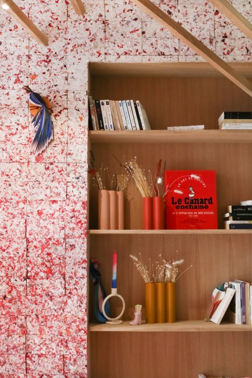 Regalwand mit roter FabBRICK-Fliesenfläche und dekorativen Objekten.