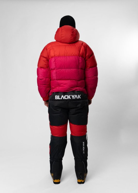 Rückansicht einer Person in einem voluminösen Expeditions-Daunenanzug in Rot und Schwarz.