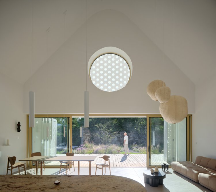 Blick ins Wohnzimmer. Die Fassade schmückt im oberen, spitzzulaufenden Teil ein rundes Fenster mit Holzausschnitten.