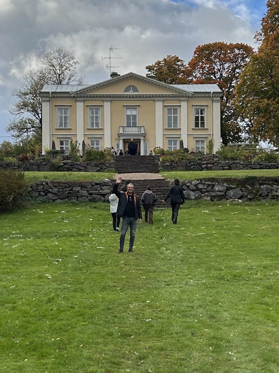 Mann steht vor Haus und winkt
