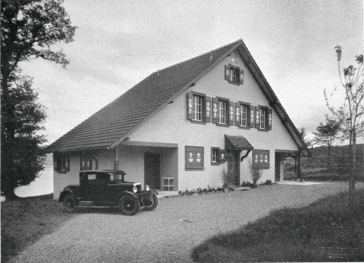 freistehendes Einfamilienhaus mit Satteldach und Fensterläden, davor steht ein Auto.