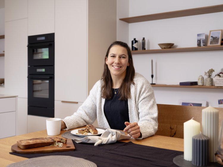 Wendy Holdener sitzt am Tisch vor ihr das selbstgebackene Bananenbrot.
