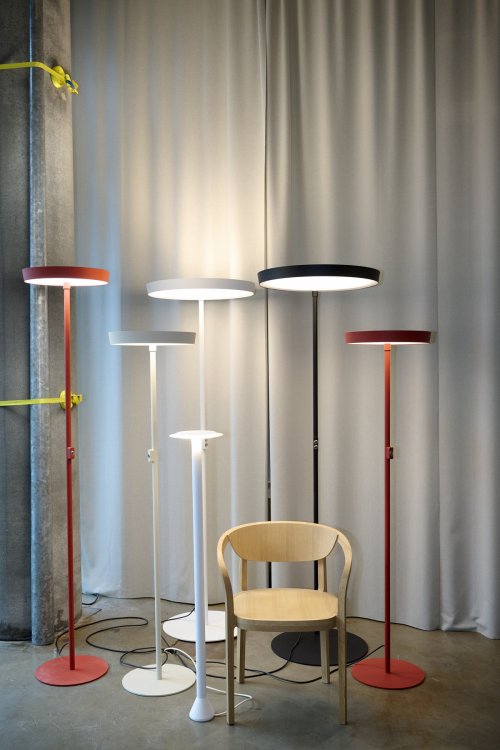 Diverse bunte Hänge- und Stehleuchten dazwischen ein Holzstuhl.