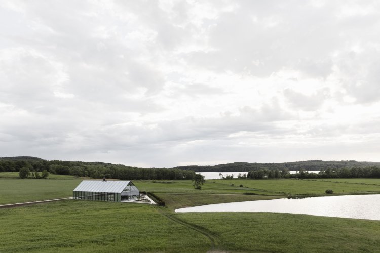 Glashaus inmitten eines grossen Feldes mit einem anliegenden See