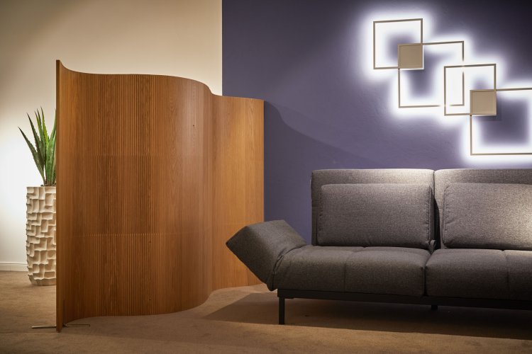 Brauner Paravent steht in einem Raum mit schwarzem Sofa.