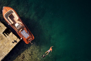 Blick von oben auf ein Boot und einem Schwimmer.