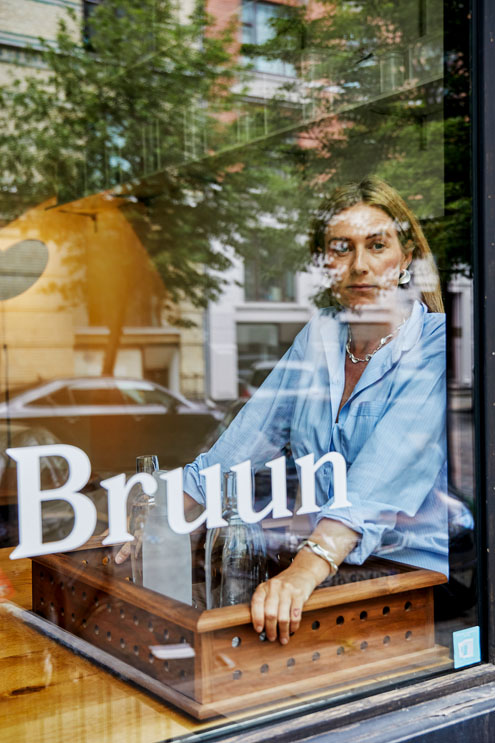 Eine blonde Frau schaut aus einem Schaufenster heraus.