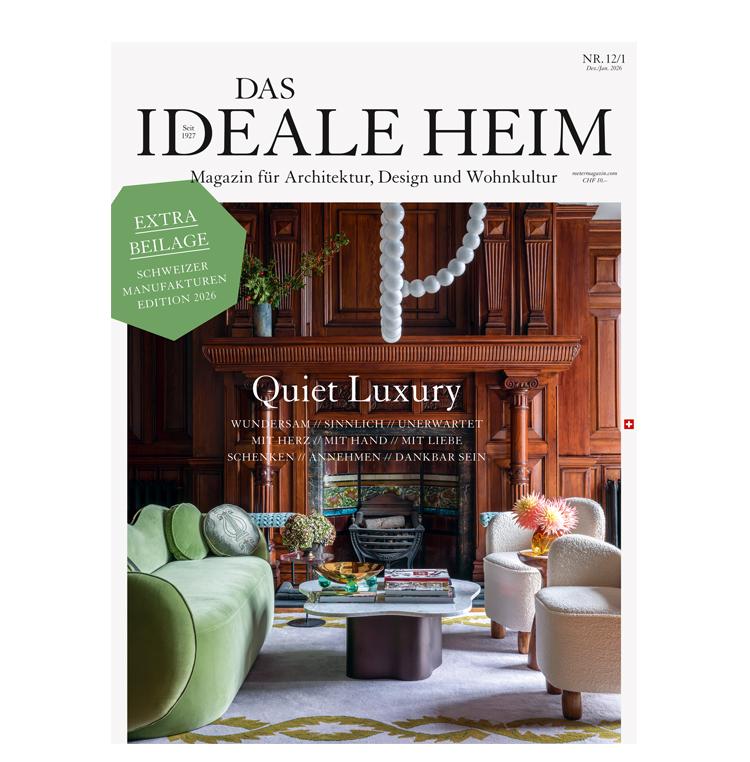 Grünes Sofa und zwei weisse, organisch geformte Sessel stehen vor einer mit Holz verkleideten Wand mit opulenter Feuerstelle.