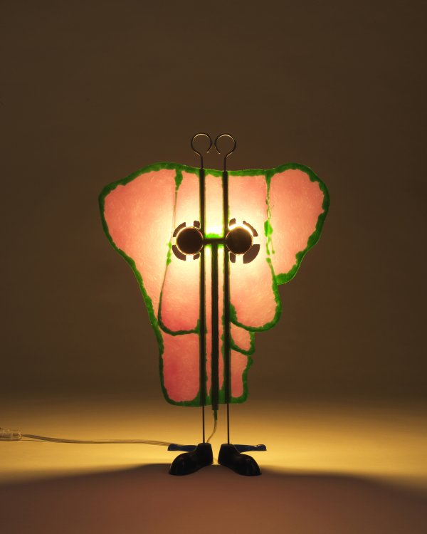 Die Leuchte Friend besteht aus gelb erhelltem Kunststoff und wirkt wie ein alienartiges, organisch geformtes Strichmännchen.