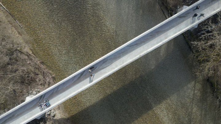 Vogelperspektive auf eine lange schmale Brücke mit einigen Passanten drauf.