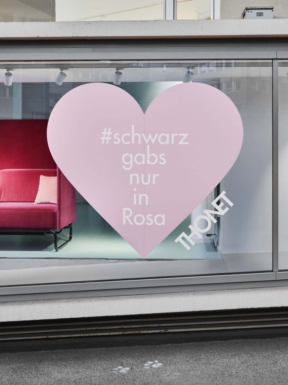 Ein Schaufenster auf dem ein hellrosa Herz mit dem Schriftzug schwarzgabsnurinrosa klebt, dahinter ist ein rotes Sofa ausgestellt zu sehen.